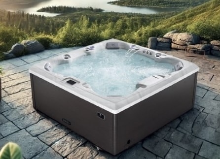 arcticpro spabad ute på en steinbelagt platting med utsikt over skog og vann